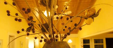 A vase with a spiral design on a table in a room with wooden ceiling and yellow walls.