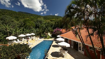 Una piscina al aire libre, sombrillas, sillones reclinables de piscina