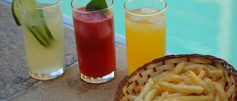 Three glasses of beverages with a basket of fries.