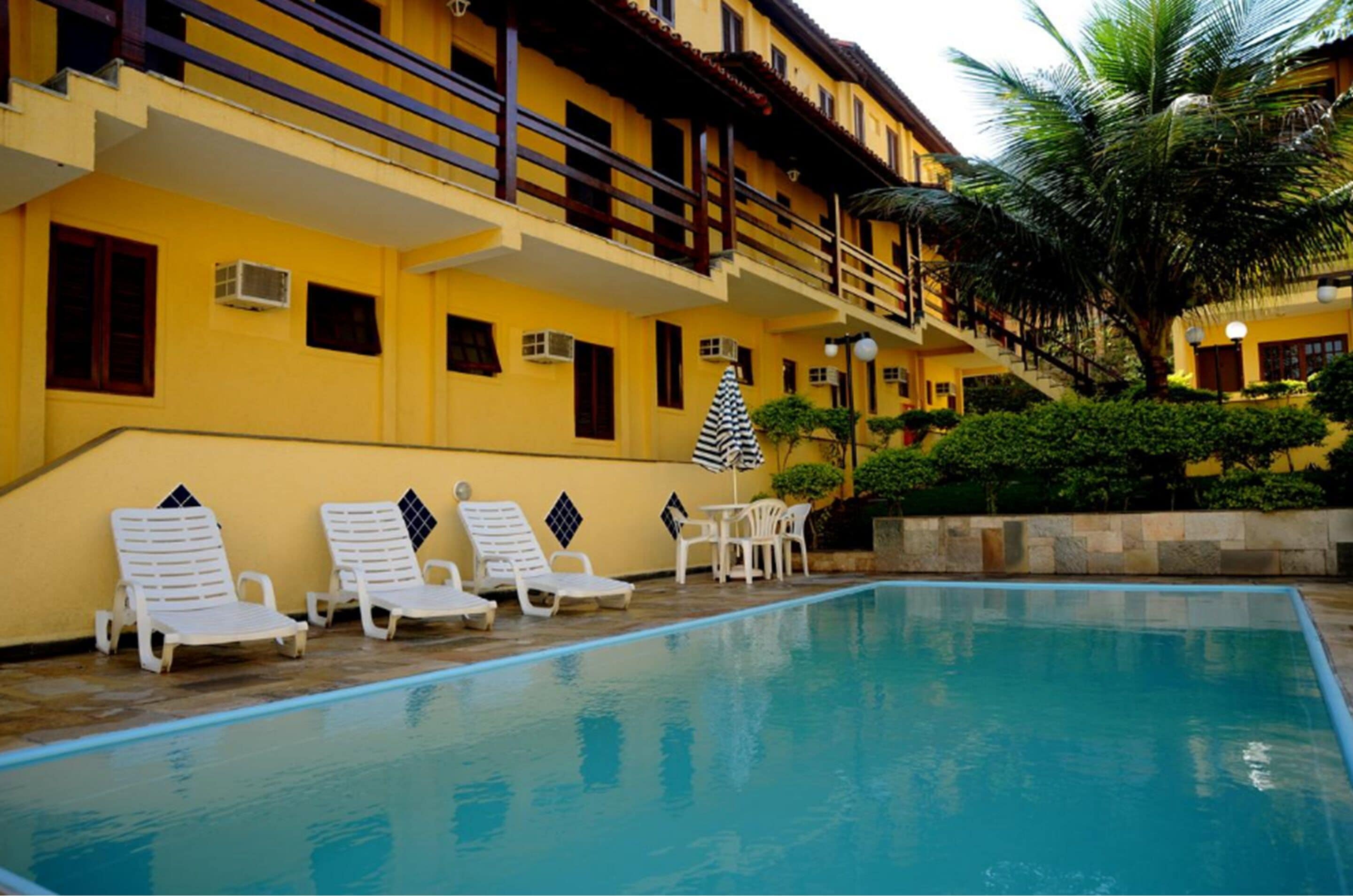 A swimming pool with lounge chairs and a staircase leading to a balcony.