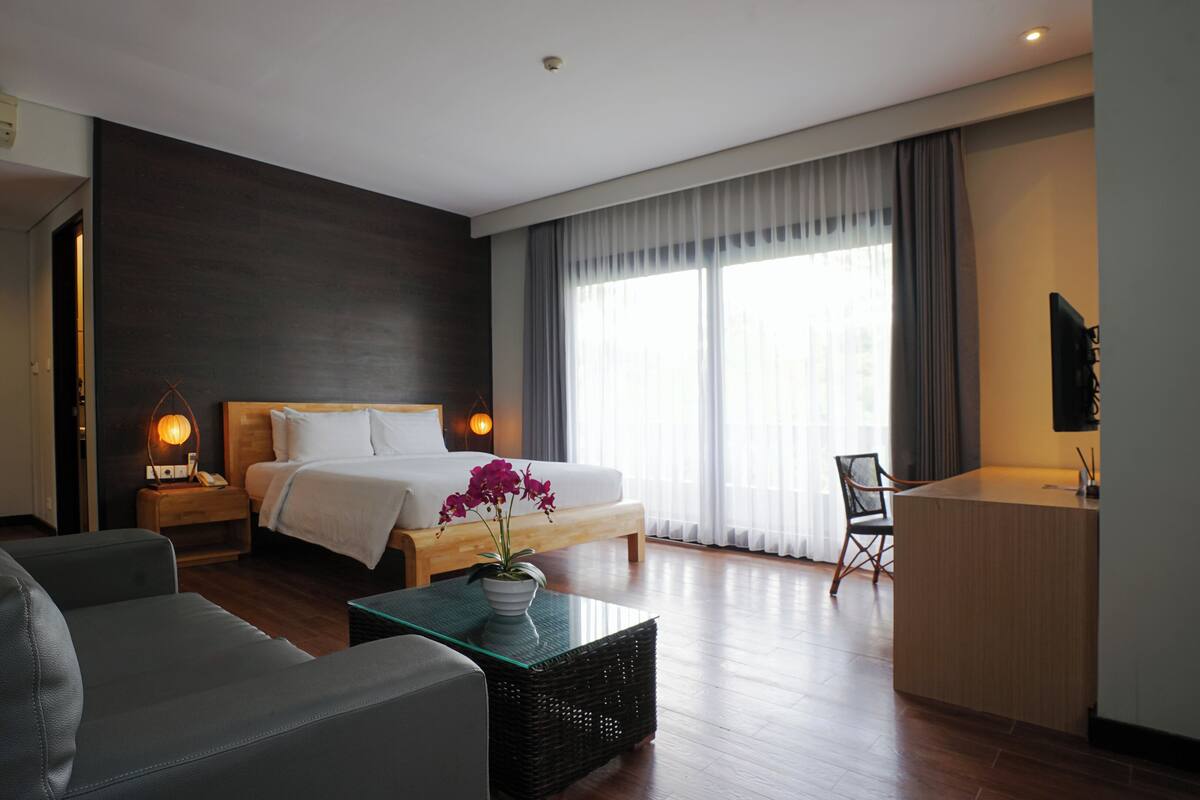 Une chambre d’hôtel moderne, dotée d’un grand lit, d’un canapé, d’un bureau et offrant une vue sur l’extérieur.