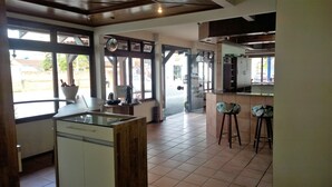A spacious kitchen with large windows, a central island, and bar stools. - Hotel Piçarras (Picarras)