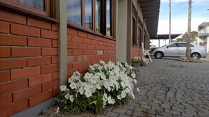 A building with a brick facade, a paved driveway, and a parked car. - Hotel Piçarras (Picarras)