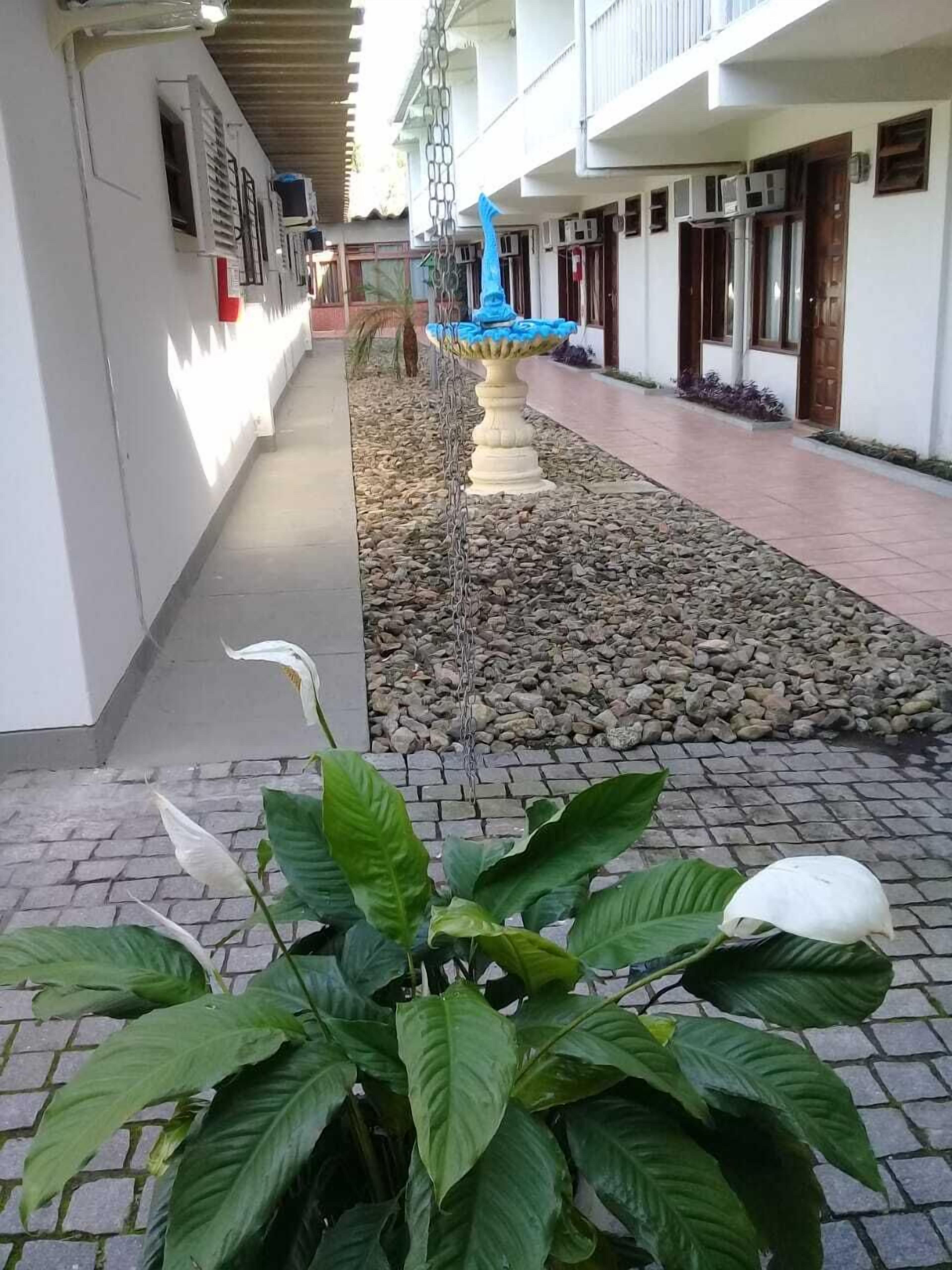 A corridor with a fountain, potted plants, and a tiled walkway.