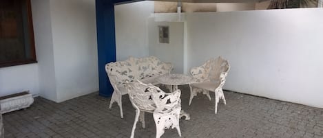 A patio with a white table and chairs, a blue pillar, and a concrete ceiling.