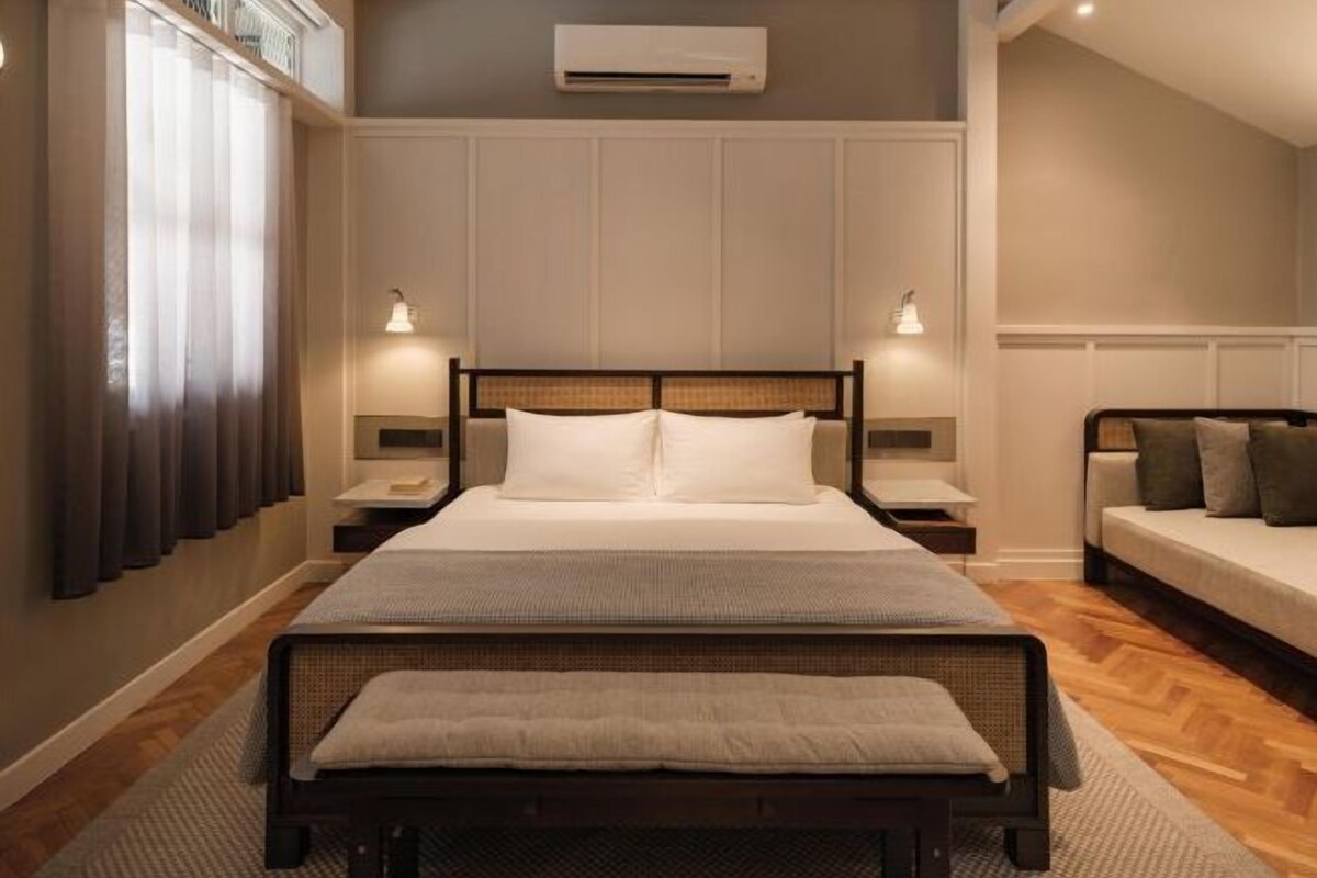 Ein Schlafzimmer mit Bett, Nachttischen, einer Bank, einem Sofa und einer Klimaanlage.