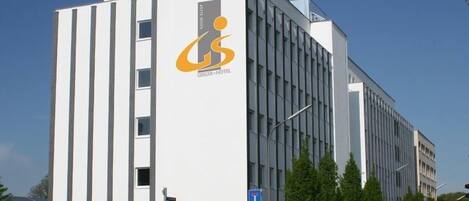 A modern hotel building with a prominent logo and a parking sign.