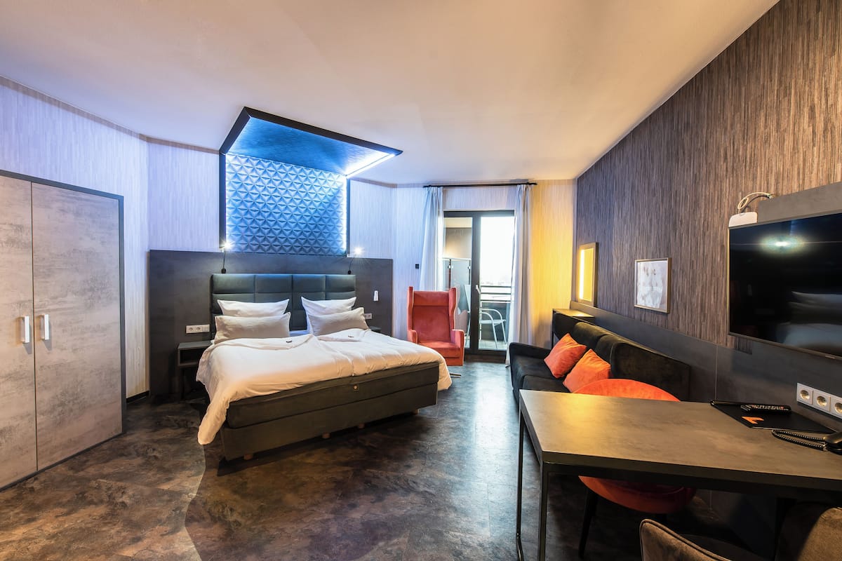 Moderni hotellihuone, jossa on sänky, työpöytä ja televisio.