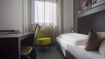 A hotel room with a bed, a desk, and a chair.