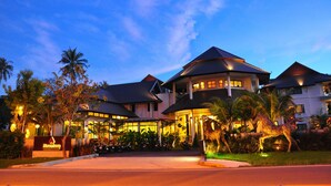 Un hotel con diversi edifici, un ingresso ben illuminato e vegetazione circostante.