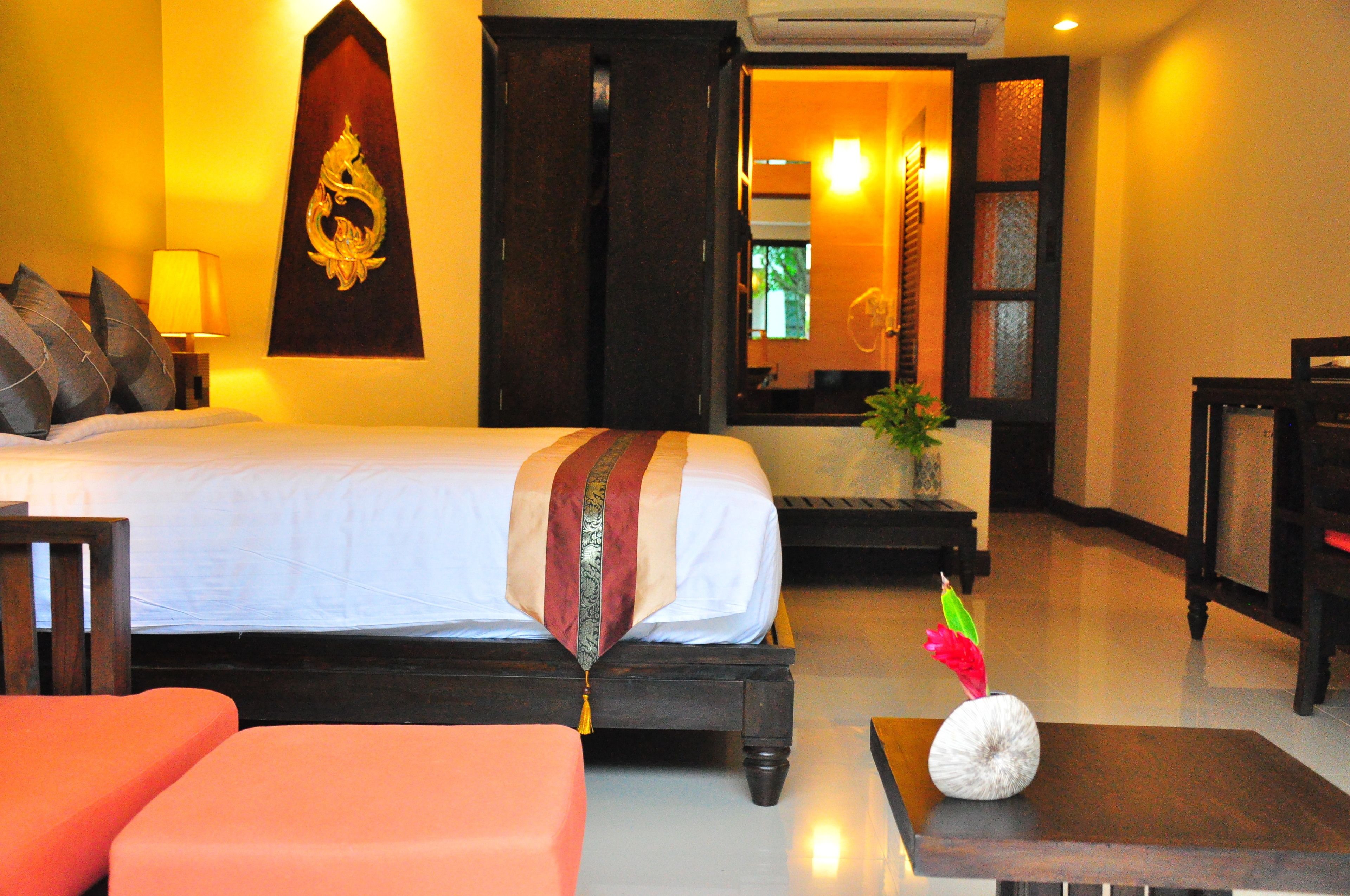 Habitación de hotel con cama, escritorio, silla y una mesita con un objeto decorativo.