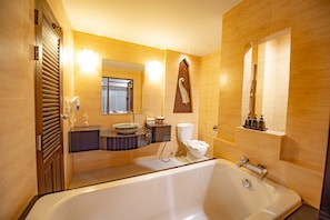 A modern bathroom with a bathtub, toilet, sink, and mirror.