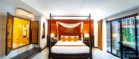 A four-poster bed with a canopy, a large mirror, and a view of the outdoors.