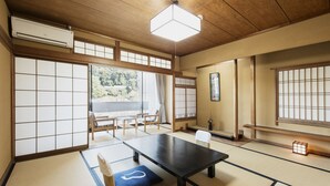 A traditional Japanese room with tatami flooring, a low table, sliding doors, and a view of the outdoors. - Seizansou (Uji)