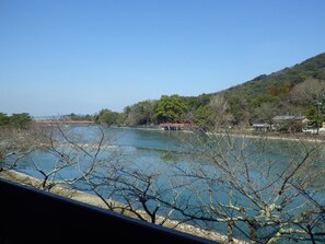 A river with a bridge, trees, and buildings in the background. - Seizansou (Uji)