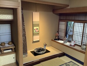 A traditional Japanese room with tatami flooring, a shoji screen, a hanging scroll, and a small table with a tea set. - Kamuro An (Kyoto)
