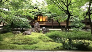 A traditional Japanese-style garden with a wooden deck, large rocks, and lush greenery. - Kamuro An (Kyoto)