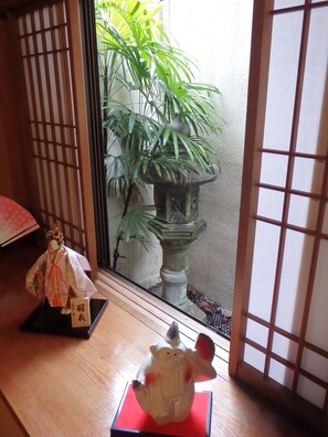 A traditional Japanese room with tatami flooring, a shoji screen, a bonsai tree, a lantern, and a decorative doll. - Kamuro An (Kyoto)