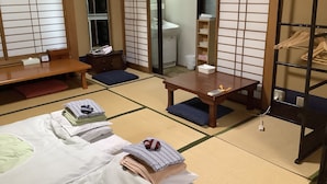 A traditional Japanese-style room with tatami flooring, a low table, a sofa, and a wardrobe with wooden hangers. - Kamuro An (Kyoto)