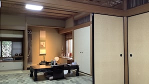 A traditional Japanese room with tatami flooring, a low table with a lamp, and sliding doors. - Kamuro An (Kyoto)