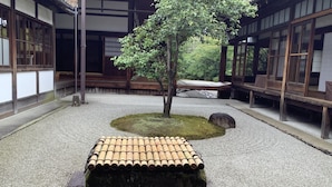 A traditional Japanese garden with a central tree, a stone lantern, and a wooden bench. - Kamuro An (Kyoto)