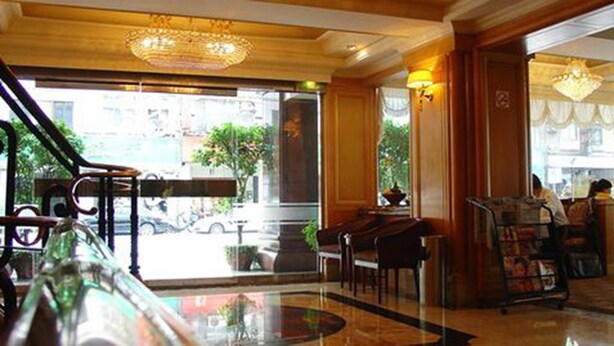 A lobby with a glass partition, a chandelier, a reception desk, and a coffee machine. - Meadow Hotel (Taipei)