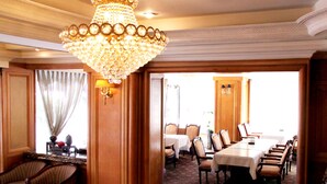A dining area with a chandelier, wooden paneling, and a table set for a meal. - Meadow Hotel (Taipei)