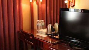 A hotel room with a wooden desk, two chairs, a television, and wall-mounted lamps. - Meadow Hotel (Taipei)