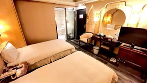 A hotel room with two beds, a desk with a chair, a television, and a bathroom visible through an open door. - Meadow Hotel (Taipei)