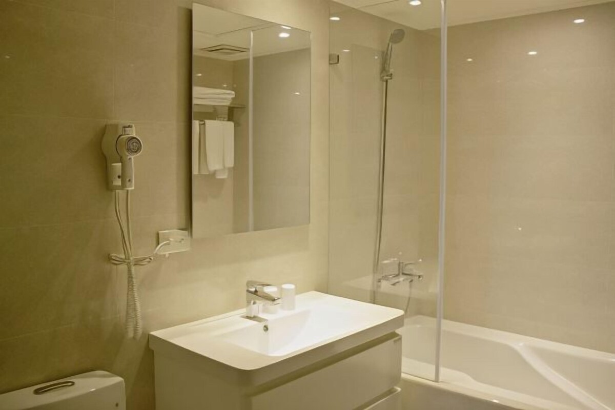 Une salle de bain moderne avec une douche à parois de verre, un lavabo blanc et un grand miroir.