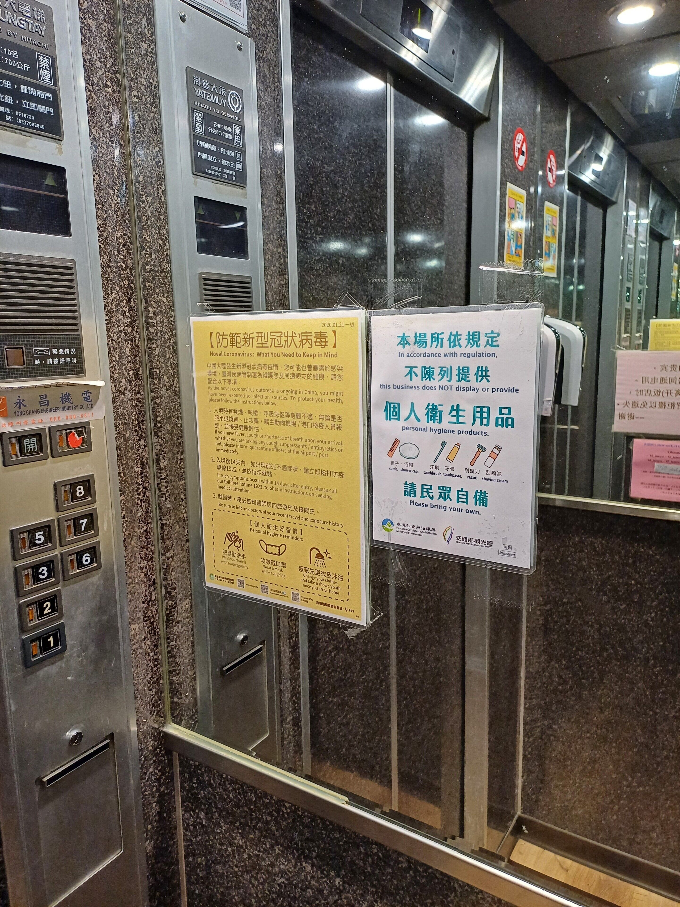 An elevator interior with multiple signs and instructions, including health and safety guidelines.