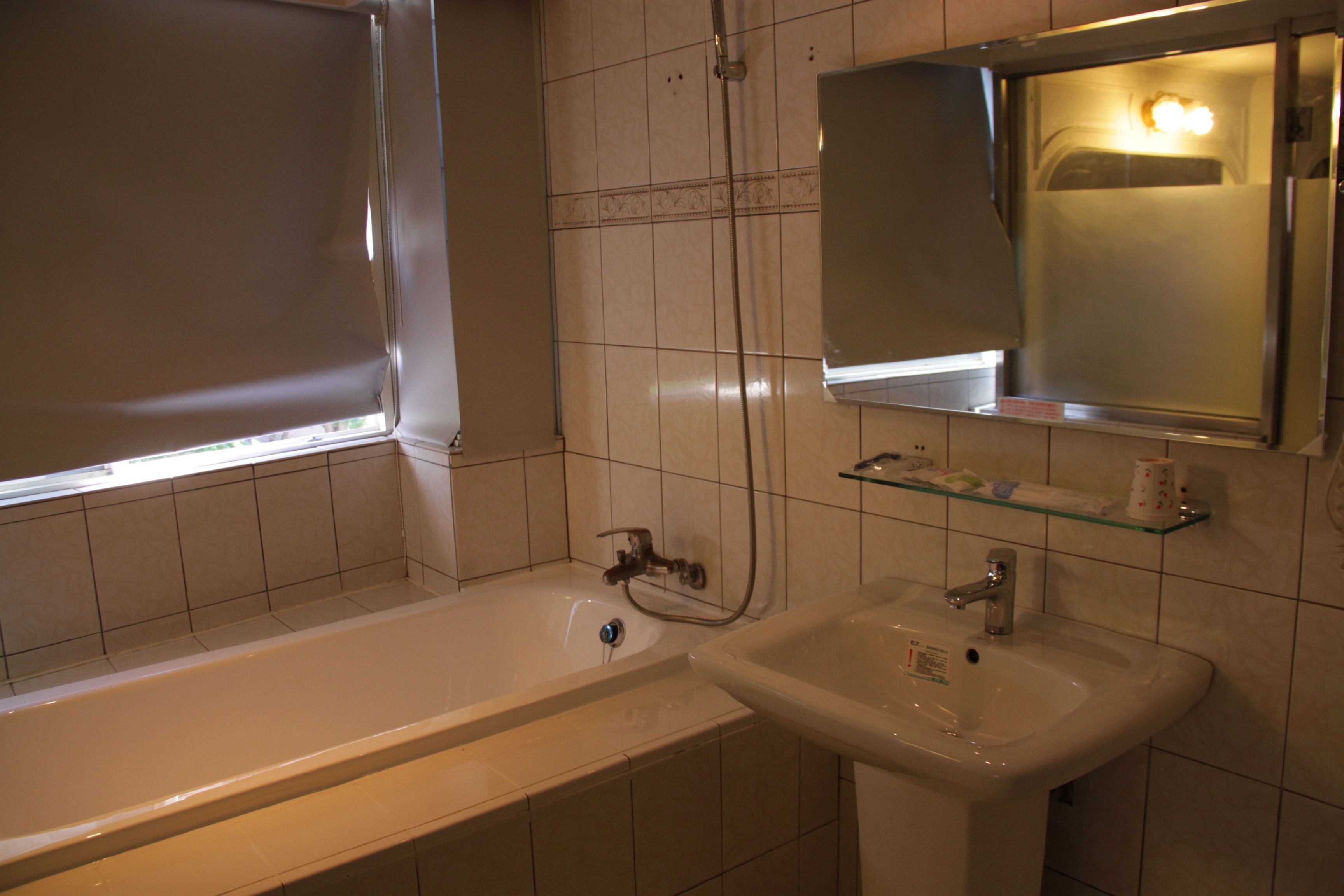 A bathroom with a bathtub, a sink, and a mirror.