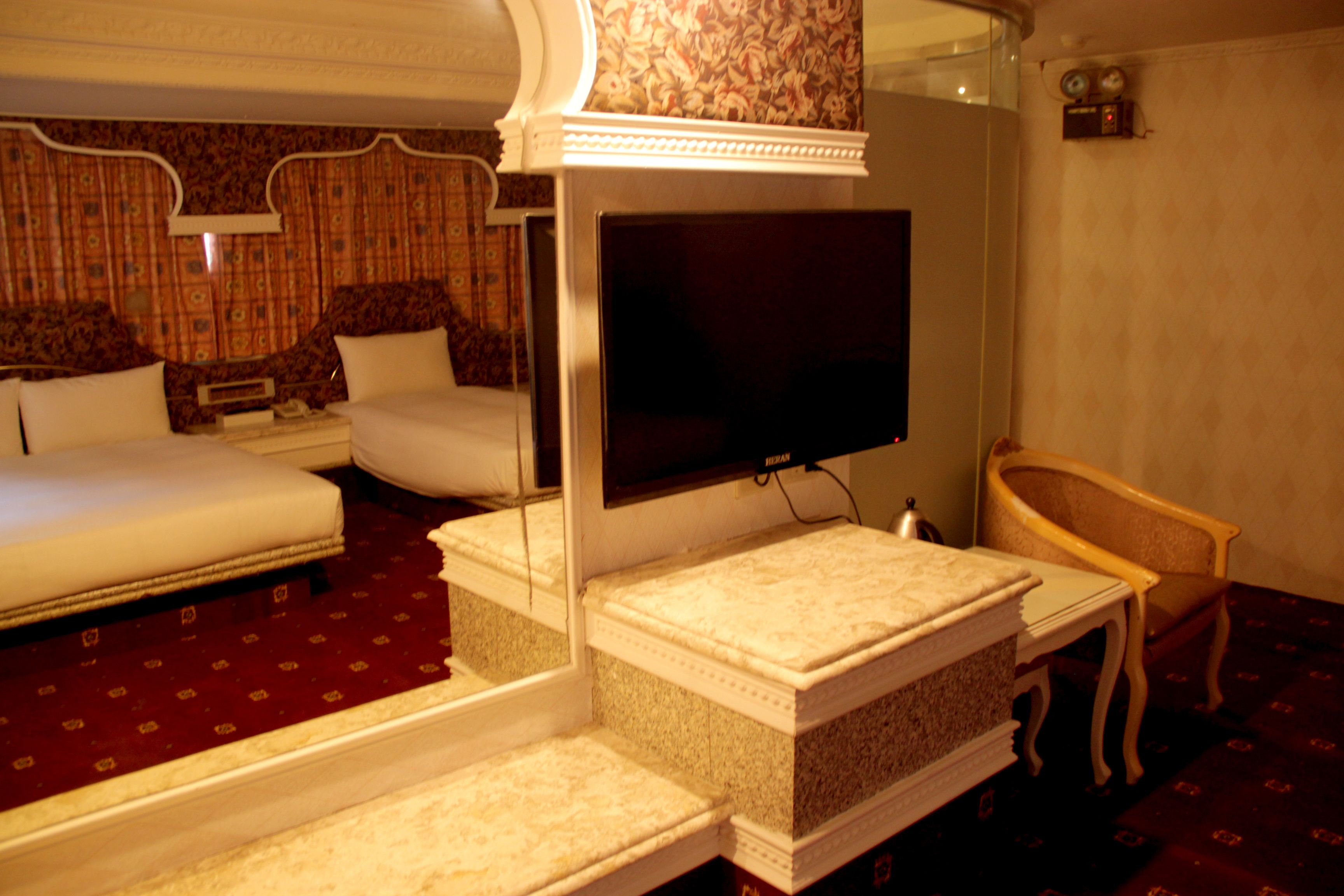 A hotel room with a large bed, a television, a chair, and a small table.