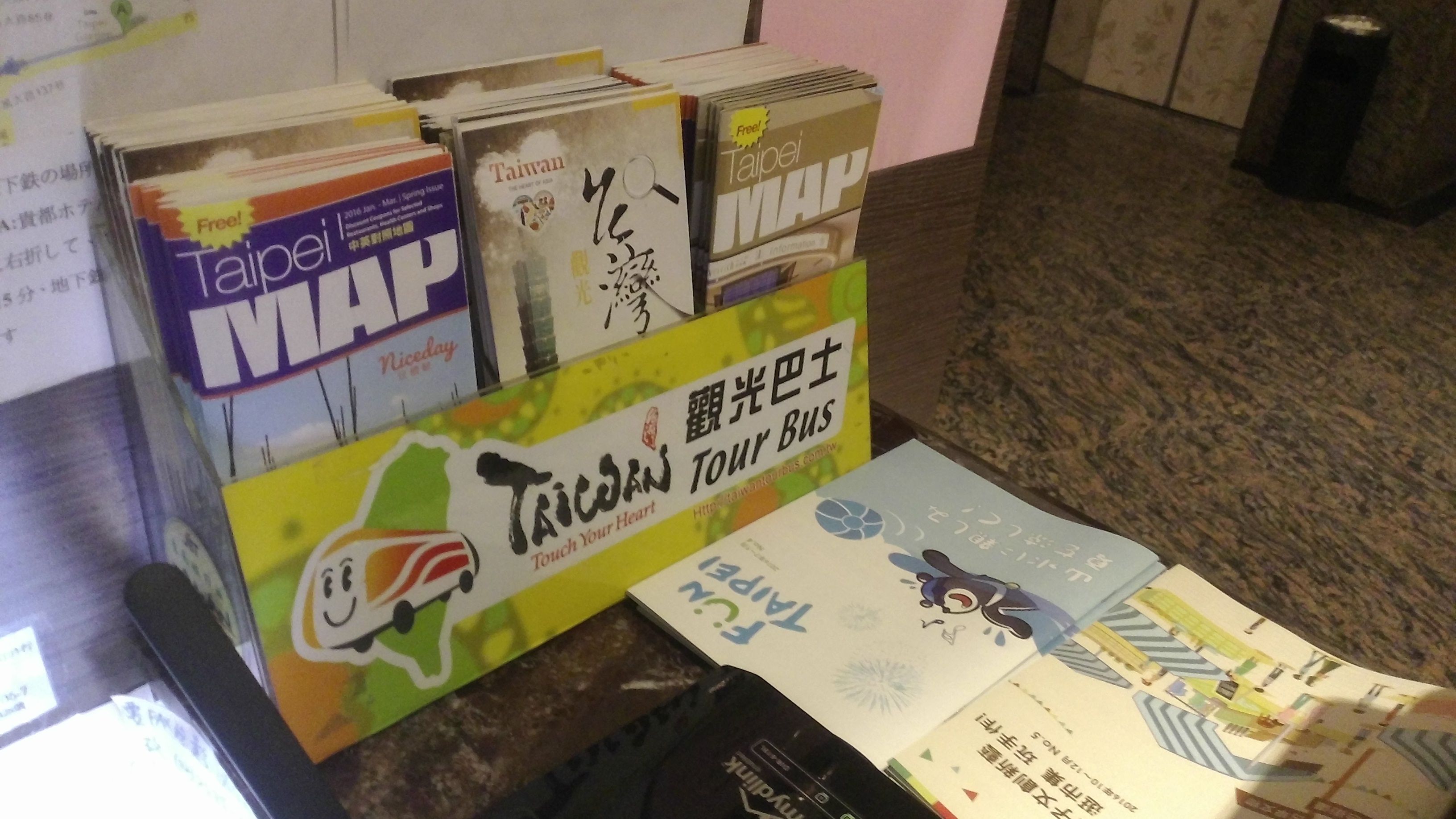 A display of travel maps and brochures for Taiwan, including a 'Taipei Map' and a 'Tour Bus' guide.
