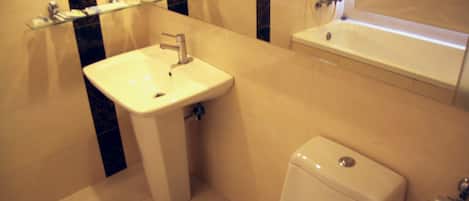Un baño con lavamanos blanco, inodoro y bañera.