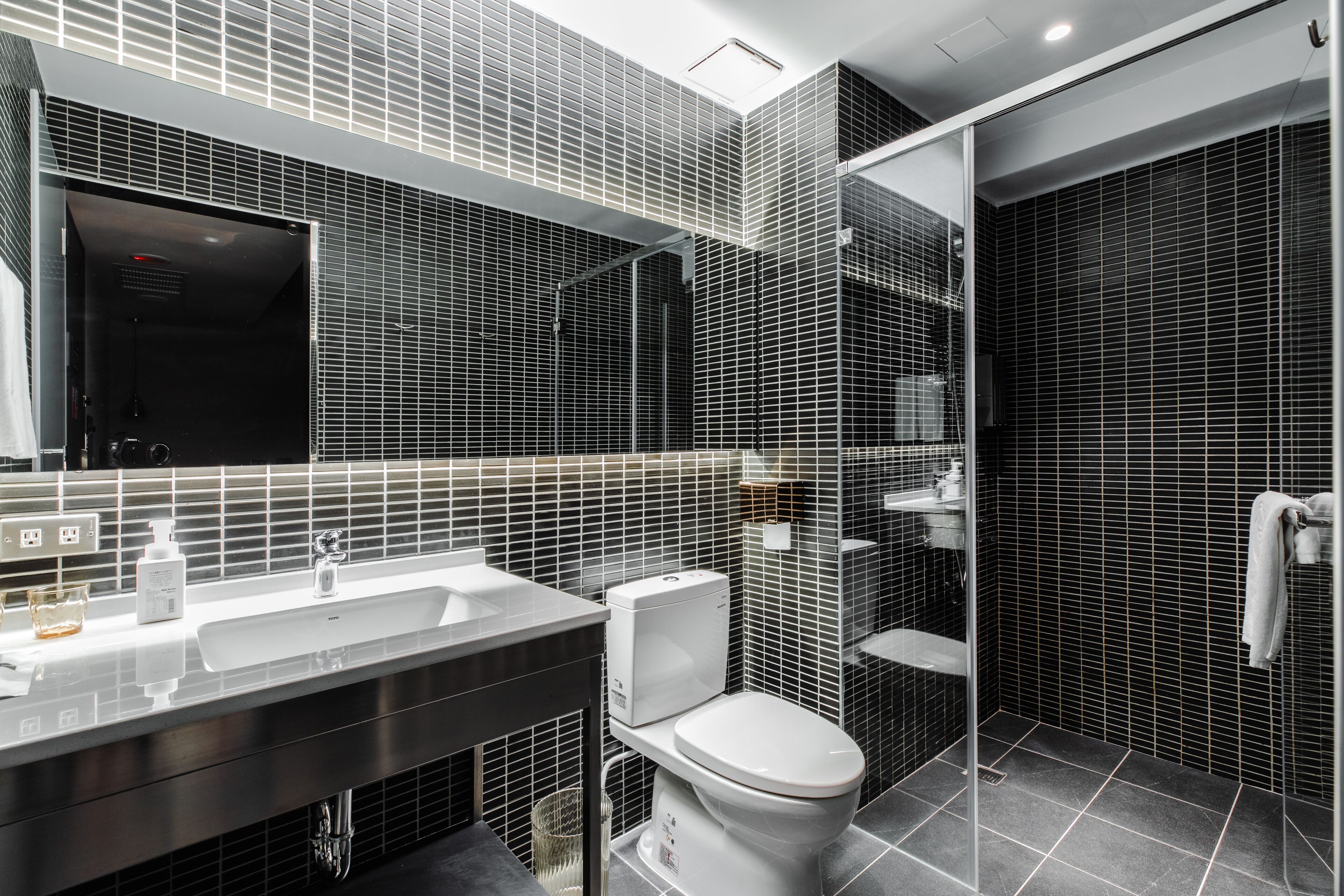 A modern bathroom with a large mirror, white sink, and a toilet.