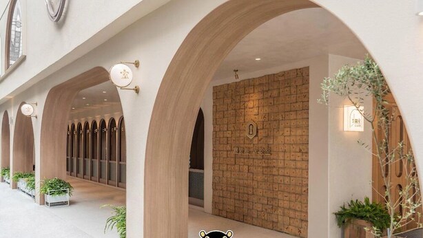 A corridor with arched ceilings, a brick wall with a sign, and potted plants. - inns hotel (Kaohsiung)