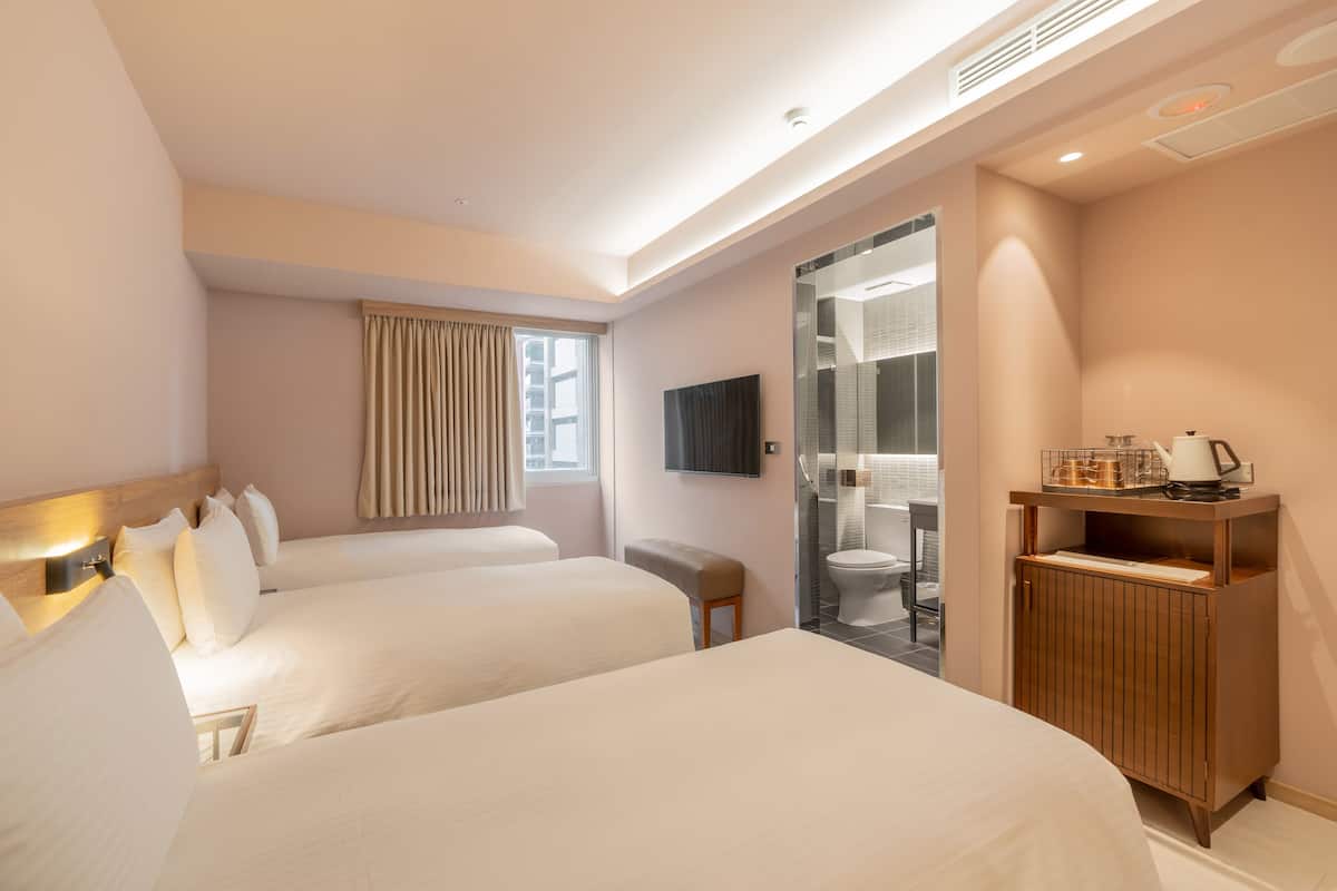 A hotel room with two beds, a wooden cabinet with a kettle, and a television on the wall.