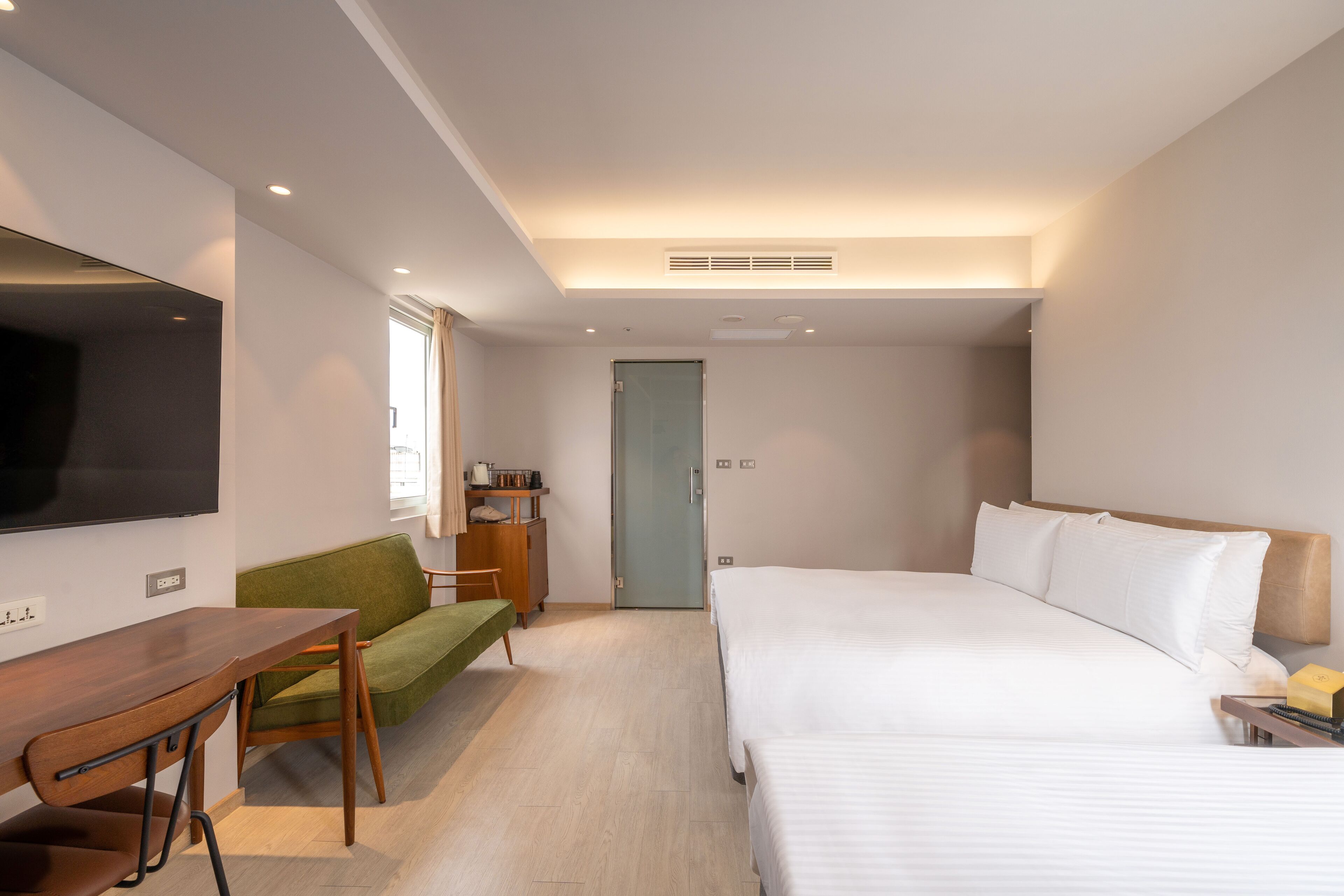 Una habitación de hotel con una cama, un escritorio, una silla, un televisor y una puerta.
