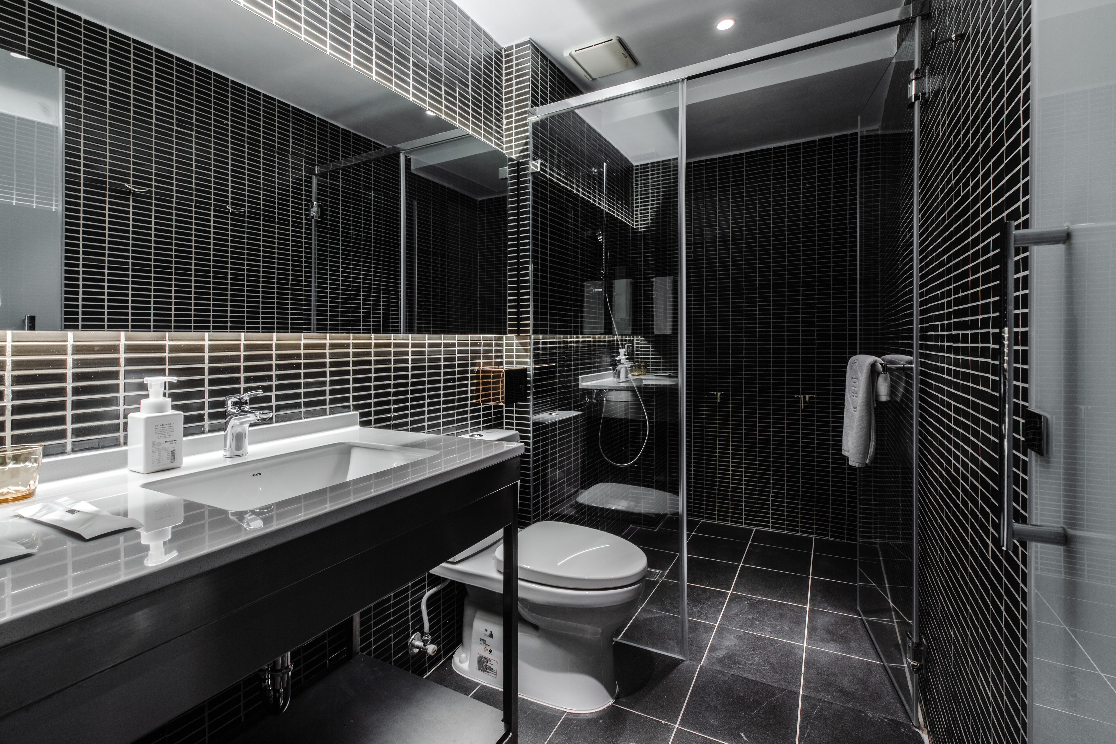 Een moderne badkamer met een grote spiegel, een wastafel, toilet en een douchehoek.
