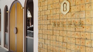 A hotel entrance with a wooden wall design, a reception desk, and a door with a keyhole. - inns hotel (Kaohsiung)