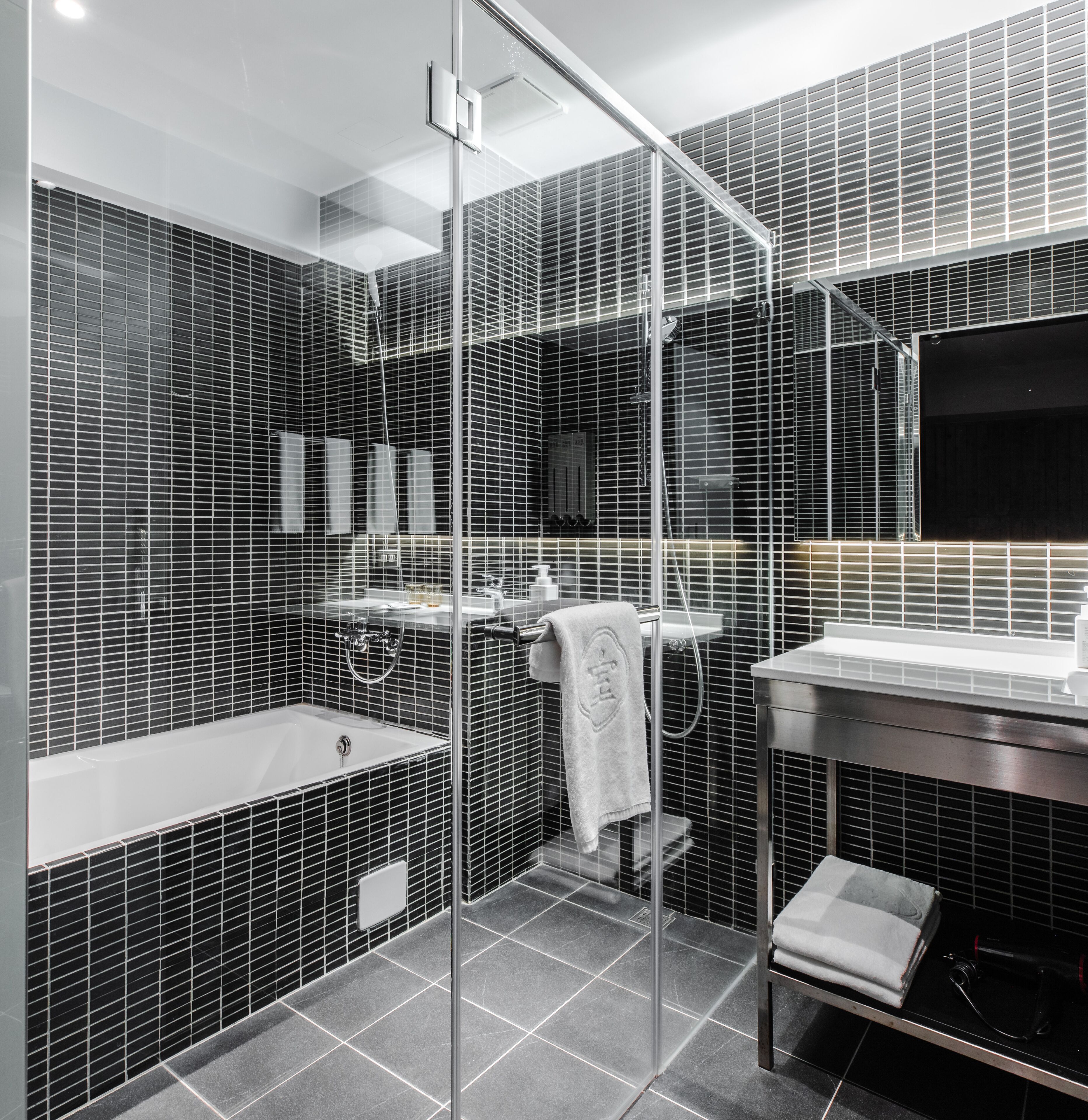 A modern bathroom with a glass shower enclosure, a bathtub, and a vanity with a mirror.