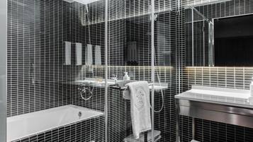 A modern bathroom with a glass shower enclosure, a bathtub, and a vanity with a mirror.
