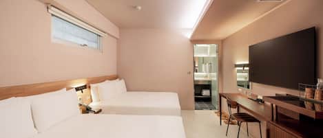 A hotel room with two beds, a desk, and a large TV.