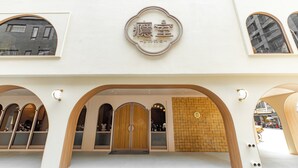 A hotel entrance with a sign, arched doorways, and a brick wall. - inns hotel (Kaohsiung)