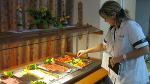 A buffet setup with various food items and a staff member serving. - Lázeňská Léčebna Mánes (Karlovy Vary)