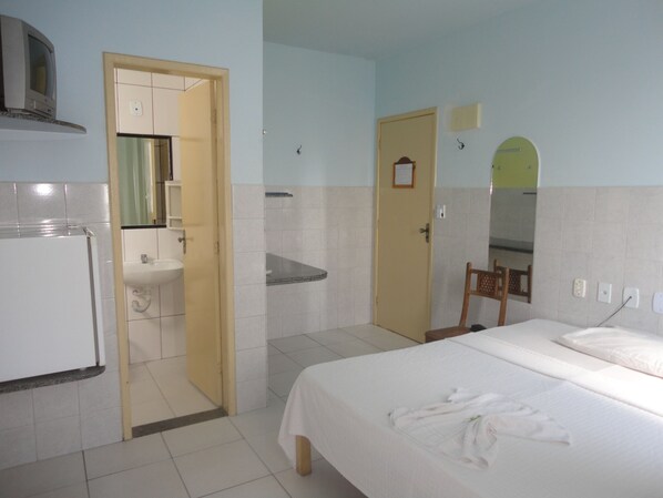Una habitación de hotel con cama, baño con lavabo y espejo.