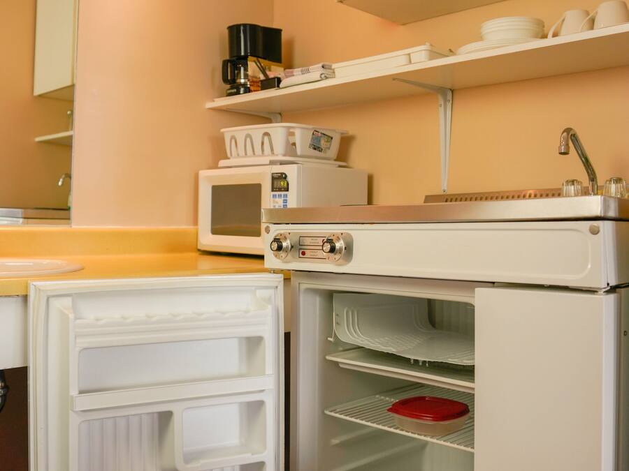 Cocina compacta con microondas, horno y refrigerador con compartimento congelador.