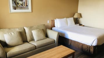 Una habitación de hotel con una cama, un sofá, una mesita y un cuadro en la pared.