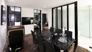 Una sala de conferencias moderna con un separador de vidrio, un televisor de pantalla plana y un comedor con una mesa y sillas de mármol negro.